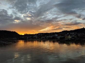 Scenic view of river by buildings against sky during sunset