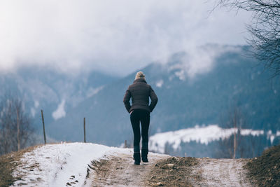 Rear view of woman walking on snow covered mountain