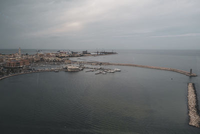 Aerial view of city by sea against sky