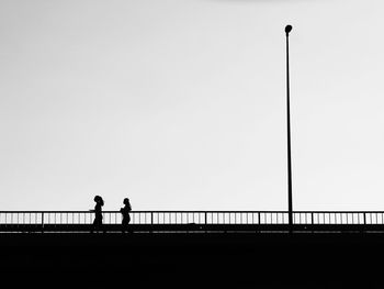 Men standing on bridge against clear sky