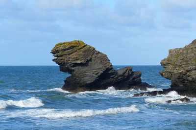 Rock formation on sea shore against sky