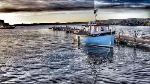 Boats moored in sea against sky during sunset