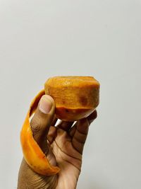 Close-up of hand holding fruit against white background