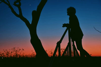 Silhouette man standing on field against sky during sunset