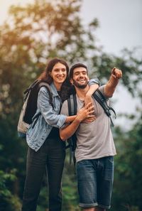 Portrait of young couple standing against trees