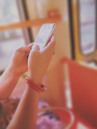 Cropped hands of woman holding mobile phone in tramway