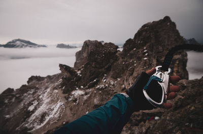 Cropped hand holding carabiner on mountain peak