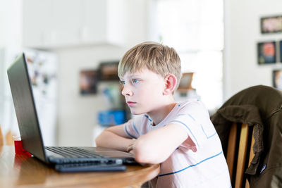 Side view of boy using mobile phone at home