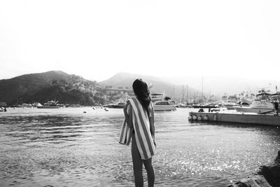 Rear view of woman standing on beach against sky