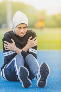 Thoughtful female athlete sitting at stadium