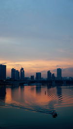 Buildings by marina barrage against sky during sunset