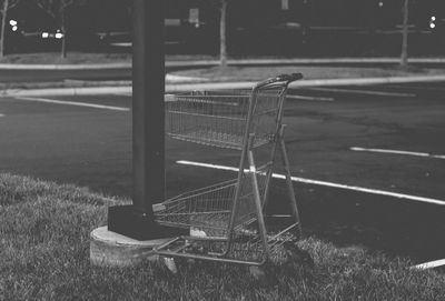 Empty shopping cart on field by road
