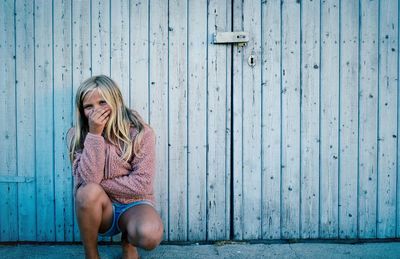 Low section of woman sitting on wooden door