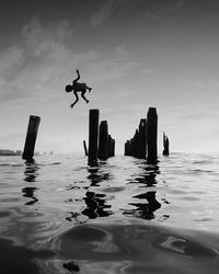 Low angle view of boy jumping in sea against sky