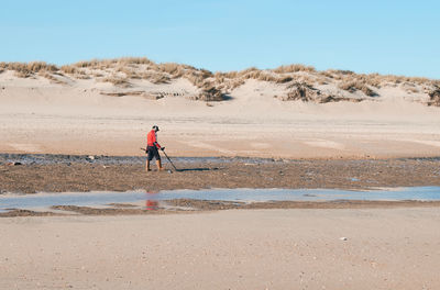 Man walking on beach against sky