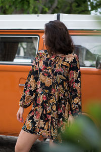 Woman standing against car on road