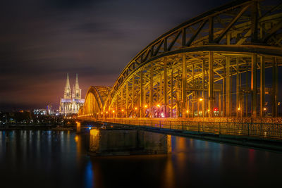 Illuminated bridge over river at night