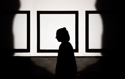 Silhouette man standing by window in museum