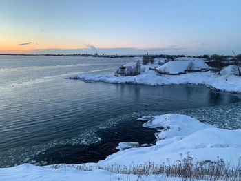 Frozen sea against sky during sunset