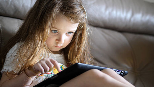 Portrait of a girl looking away while sitting on sofa at home