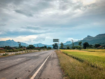 Road leading towards mountains against sky