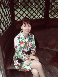 High angle portrait of smiling beautiful woman sitting on bench