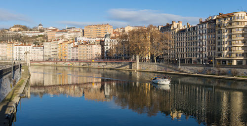 Pleasure boat sailing on the saône in lyon with the old colorful buildings reflecting in the river