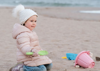 Little girl is digging in the sand on a cold day at the beach