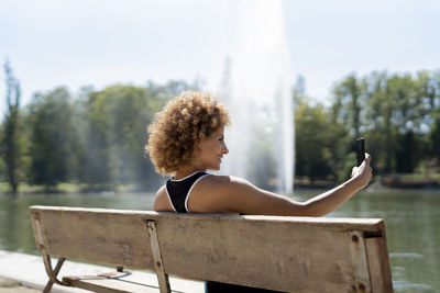 Woman on a bench by the lake taking a selfie