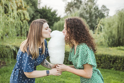 Female friends eating large cotton candy at park