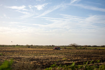 Scenic view of a tractor on an agricultural field against sky