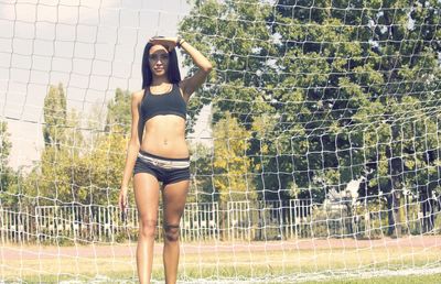 Portrait of woman standing by net on field