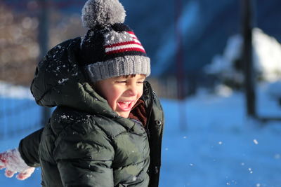 Happy cute boy playing on snow covered field