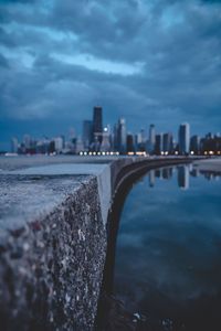 Buildings by sea against sky at dusk