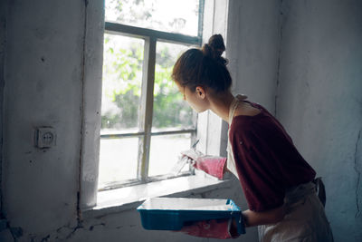 Side view of young woman looking through window