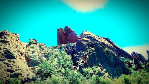 Low angle view of cliff against clear blue sky