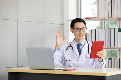 Portrait of smiling young woman using laptop on table