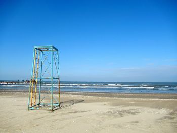 Lifeguard hut on beach against clear blue sky