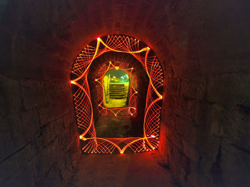 Illuminated tunnel seen through window in old building