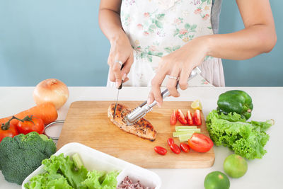 Midsection of woman with vegetables on cutting board
