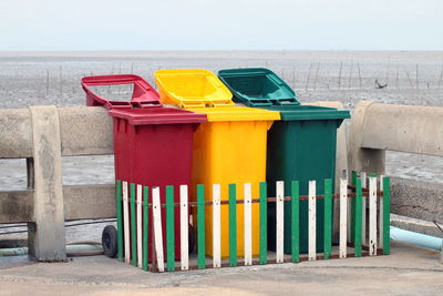 Multi colored garbage bins by railing