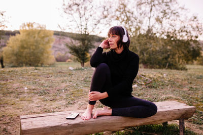 Full length of woman sitting on bench at park