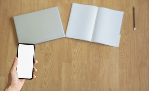 Low section of person holding smart phone on table