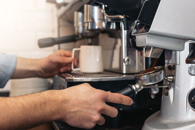 Cropped hands making coffee in cafe