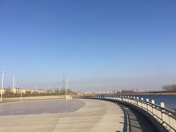 Road by sea against clear blue sky