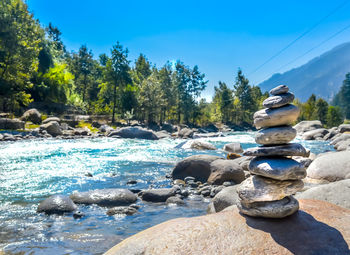 Stack of stones on shore against sky