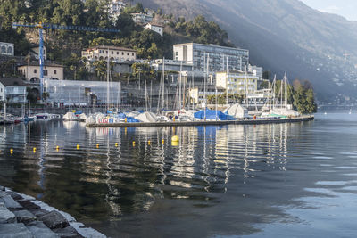 Sailboats moored in sea against buildings in city