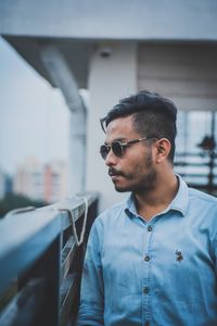 Young man looking away while standing outdoors