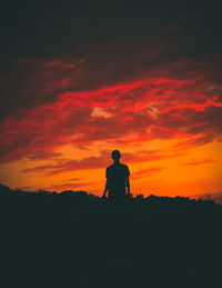 Silhouette man standing against orange sky during sunset