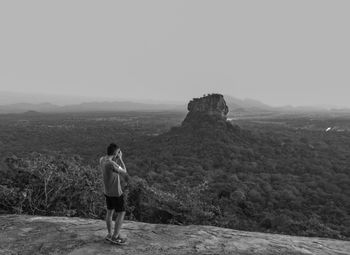 Rear view of man looking at mountain against sky